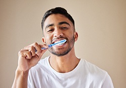 man brushing his teeth as part of oral hygiene for dental implants in Geneva