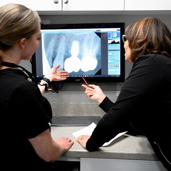 Dentist and dental team member looking at digital x-rays